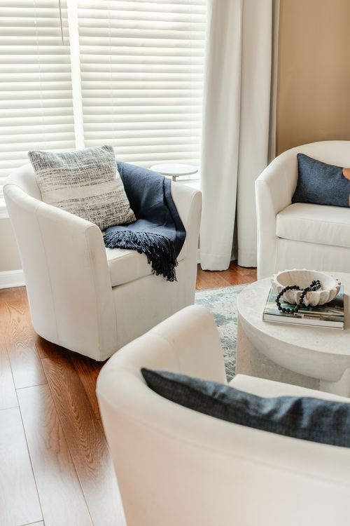 White swivel chairs with navy throw pillows arranged around a round coffee table