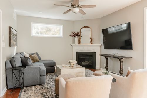 Living room with a gray sectional, corner fireplace, mounted TV and mustard-toned chairs