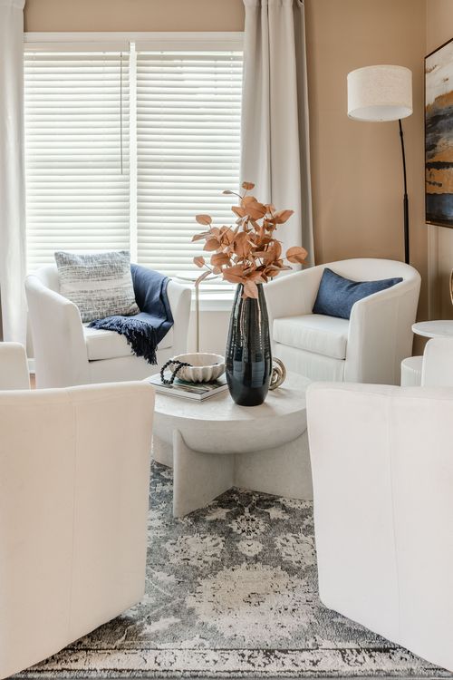 Sitting area with white swivel chairs, blue throw pillows and a marble coffee table