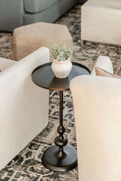 Close-up of a black pedestal side table with a ceramic vase on a patterned rug