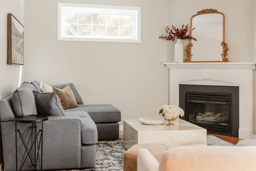 Living room corner fireplace with a gilded mirror, dried florals and gray sectional