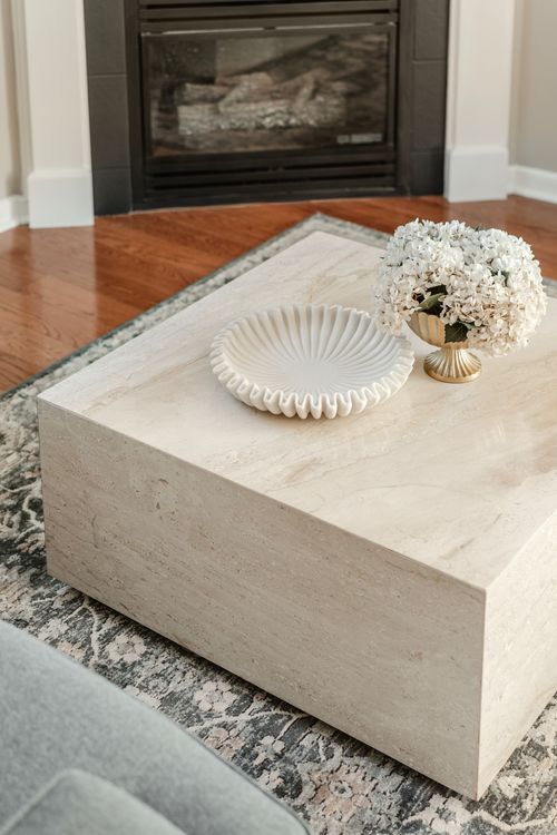 Close-up of a marble coffee table corner with a scalloped dish and hydrangea arrangement