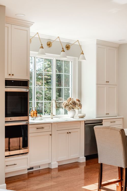 Kitchen sink area with a garden window, brass gooseneck faucet and stainless dishwasher