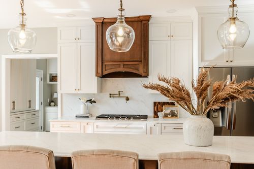 Kitchen with a wood range hood, pot filler faucet and a dried pampas grass centerpiece