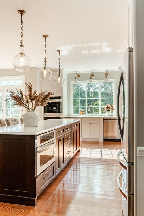 Bright kitchen with a long dark wood island, glass pendant lights and a dining table beyond