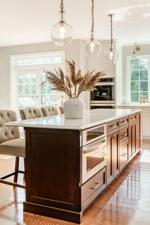 Kitchen island with white quartz counter, dried pampas grass centerpiece and glass pendant lighting