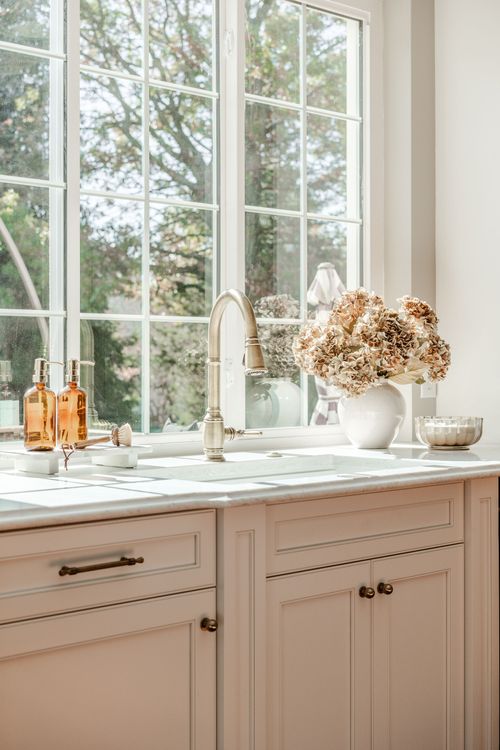 Kitchen sink with brass faucet, marble countertop and a bouquet of dried hydrangeas by the window