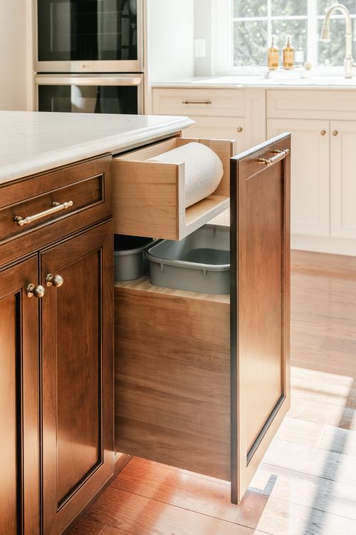 Hidden trash and paper towel pull-out drawer built into a dark wood kitchen island