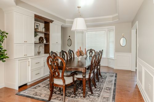 Dining room with a white built-in hutch, dark wood table and patterned area rug