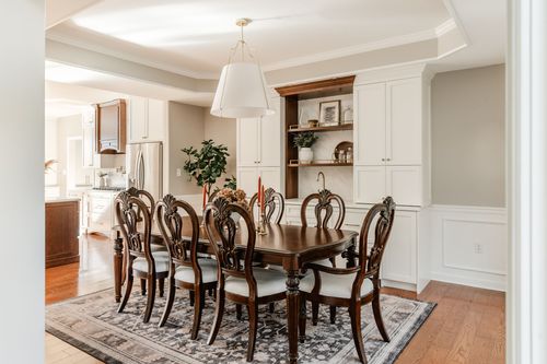 Dining room with an oversized white drum pendant over a wood table set with candles