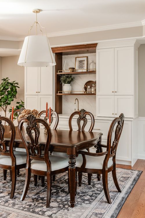 Elegant dining room with a brass-accented pendant light over a table set with candles and dried florals