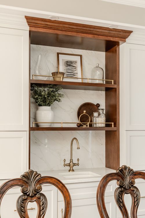 Wood open shelving styled with framed art and a vase above a marble bar sink