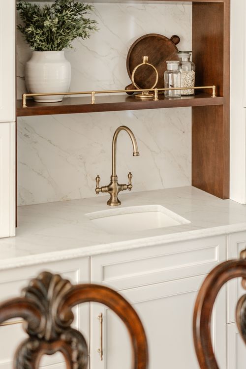 Built-in wood bar shelf with a cutting board, glass jars and a brass faucet