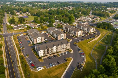 Golden-hour aerial view of a beige and gray apartment complex surrounded by rolling green hills