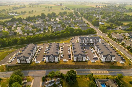 Aerial view of apartment buildings with a swimming pool and sports field visible nearby