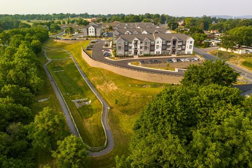 Aerial view of an apartment complex with a landscaped drainage swale and retaining wall