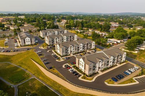 Aerial view of apartment buildings along a curved drive with hills and farmland beyond