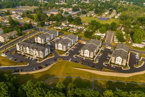 Aerial view of apartment buildings with parking lots near a fenced tennis court