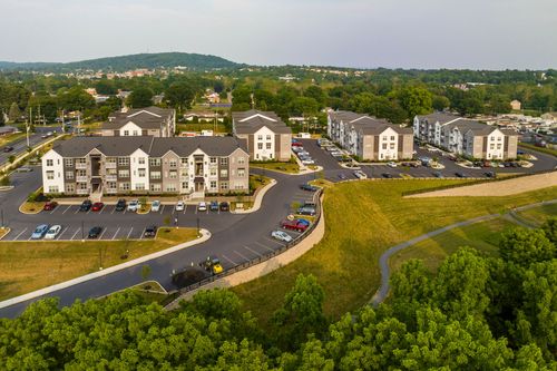 Aerial view of apartment buildings bordered by a grassy walking trail and mature trees