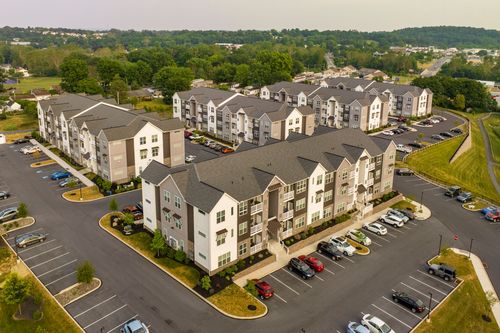 Aerial view of a cluster of tan and brown apartment buildings with landscaped parking lots