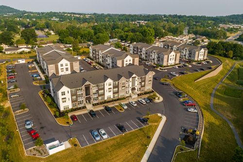 Aerial view of apartment buildings with pitched roofs, parking lots and landscaped green space