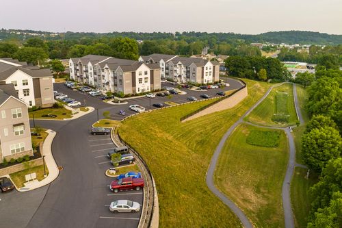 Aerial view of apartment buildings beside a grassy meadow with a paved walking trail
