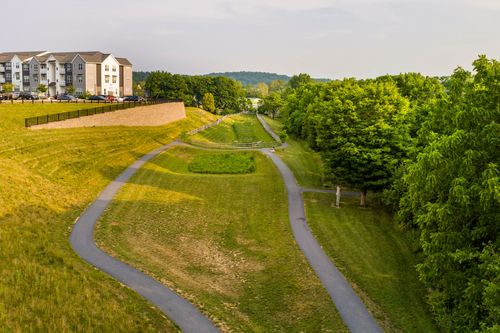 Aerial view of a winding walking trail through a grassy meadow near the apartment complex