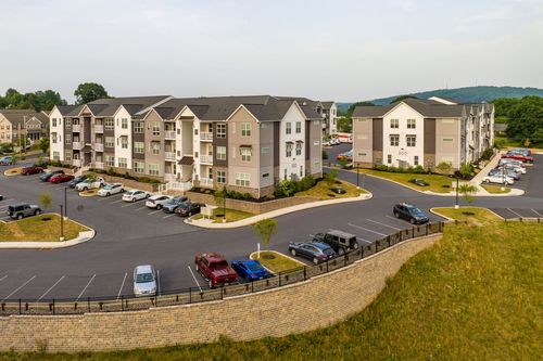Low aerial view of two multi-story apartment buildings with balconies and landscaped parking