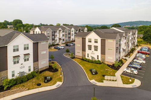 Low aerial view of two apartment buildings numbered 100 and 300 flanking a paved courtyard drive
