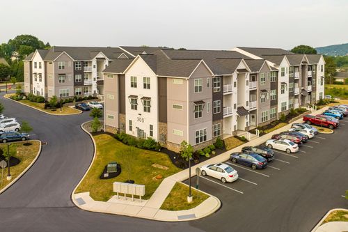 Aerial view of a three-story apartment building numbered 300 with a landscaped parking lot