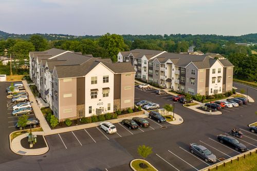 Aerial view of a large apartment building with two wings and parking lots on either side