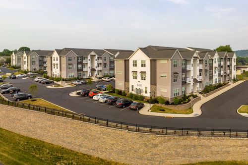 Aerial view of an apartment building beside a stacked stone retaining wall and parking lot