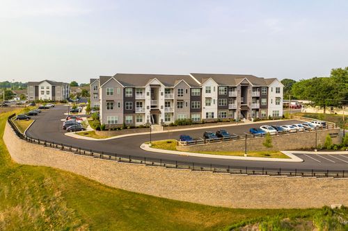 Aerial view of an apartment building parking lot bordered by a stone retaining wall and grass slope