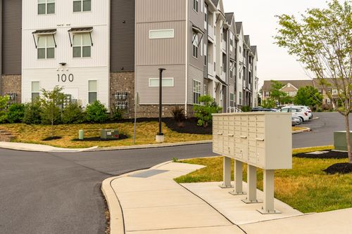 Street-level view of an apartment building numbered 100 beside a cluster mailbox stand