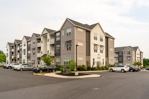 Street-level view of apartment building 400 with a landscaped entrance and parked cars