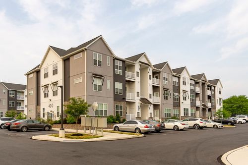 Street-level view of apartment building 400 with a directory sign and rows of parked cars