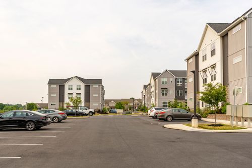 Wide street-level view of an apartment parking lot flanked by buildings on both sides