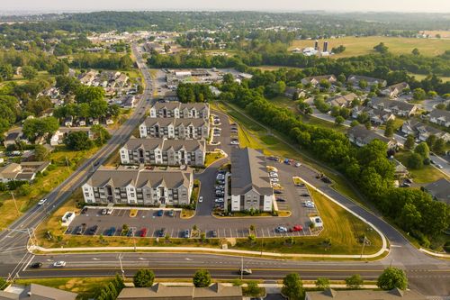Golden-hour aerial view of an apartment complex bordered by farm fields and a distant silo