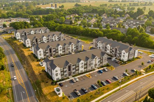Aerial view of apartment buildings and parking lots along a two-lane road at sunset