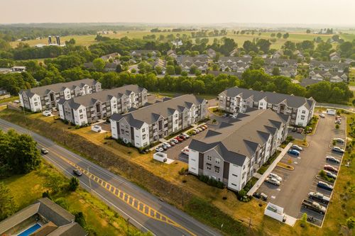 Hazy sunset aerial view of an apartment complex surrounded by farmland and mature trees
