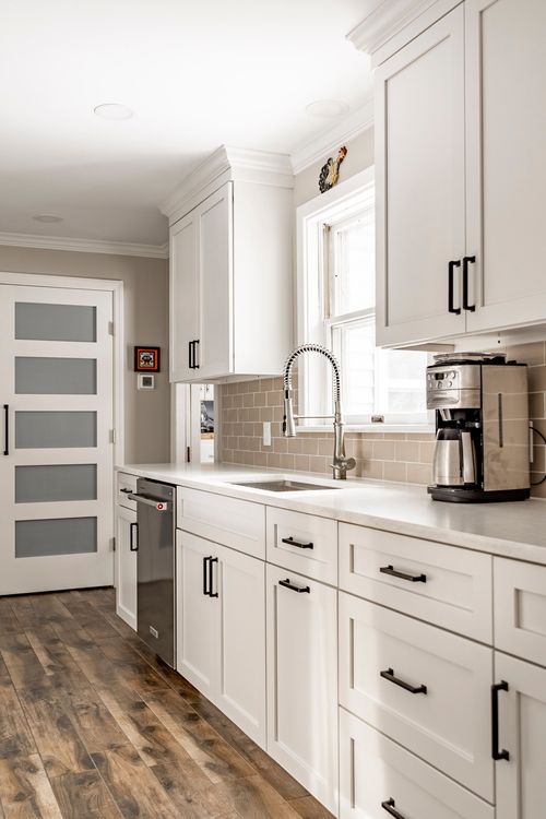 Kitchen sink with a pull-down faucet, black cabinet hardware and a subway tile backsplash