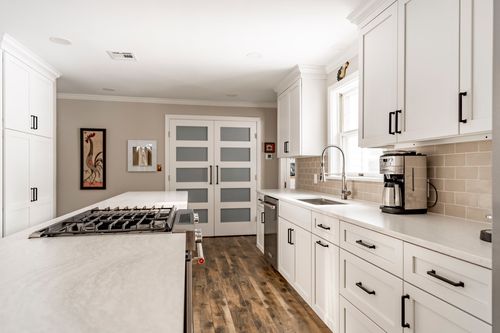 Kitchen view toward frosted glass French doors past a gas cooktop and coffee maker