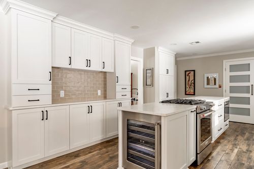 White kitchen with a gas range, built-in wine cooler and black cabinet hardware
