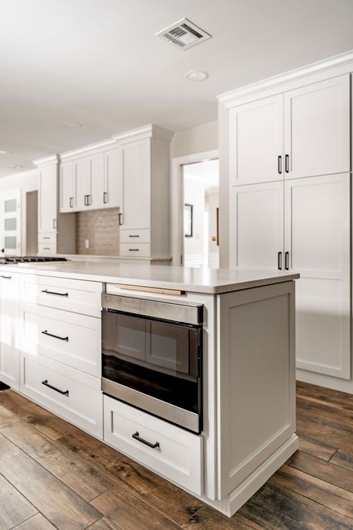 Close-up of a white kitchen island with a built-in stainless microwave drawer