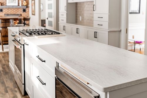White kitchen island counter with a gas range and a dining room visible beyond