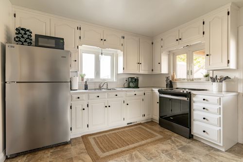 White kitchen with stainless appliances, black cabinet hardware and a garden window