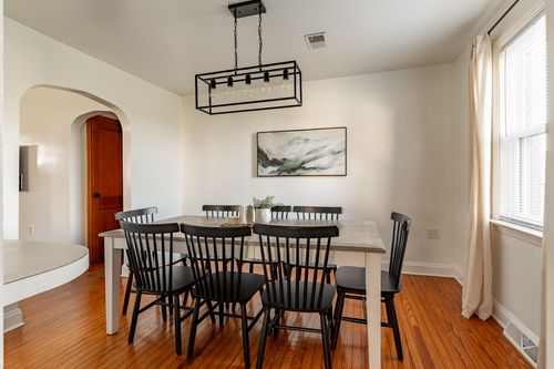 Dining room with a black spindle-back table set, a linear chandelier and abstract wall art