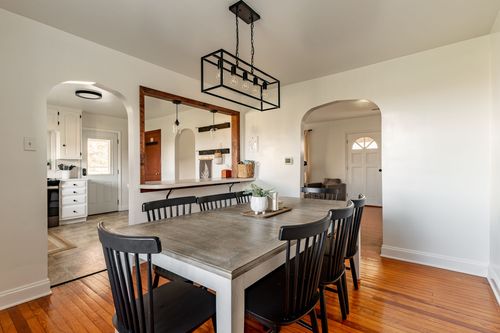 Open dining room with a black chandelier and archways leading to the kitchen and living room