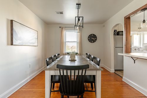 Dining room with black dining chairs, a wall clock and archways opening to the kitchen