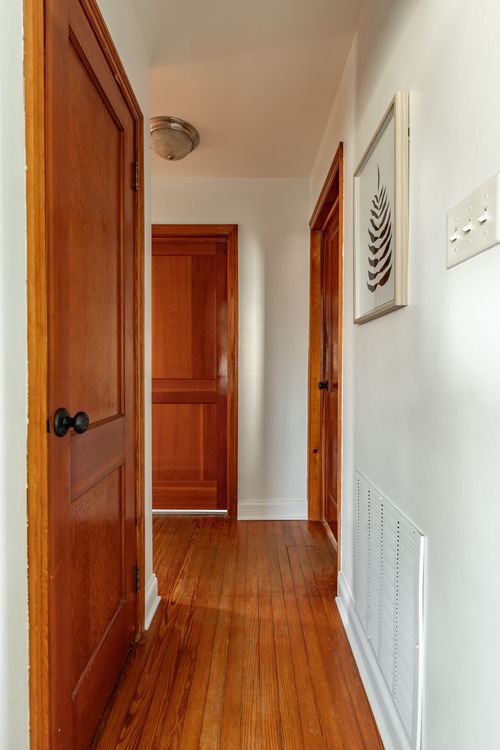 Hallway with wood paneled doors, hardwood floors and a framed botanical print